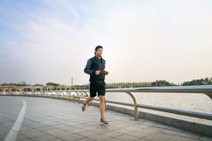 sporty man with earphones jogging at lake park