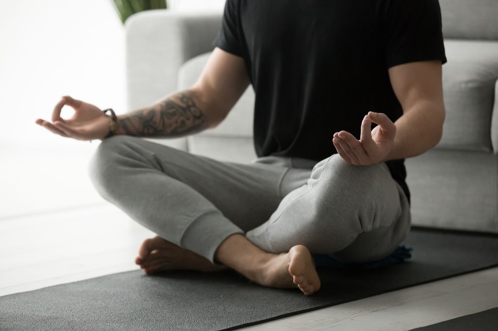 sporty man with tattoo meditating practicing yoga in lotus pose