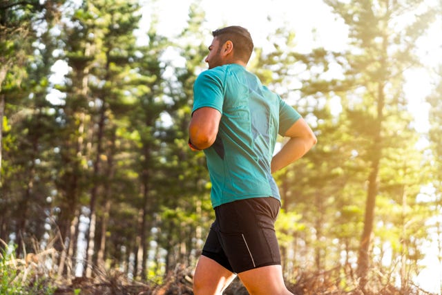 sporty mid adult man jogging against trees