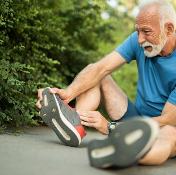 sporty senior man having leg injury outdoors
