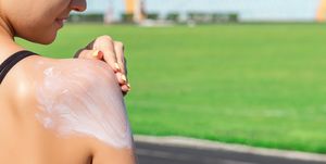 Sporty woman applying sunscreen on Sport area before run. Sports and healthy concept