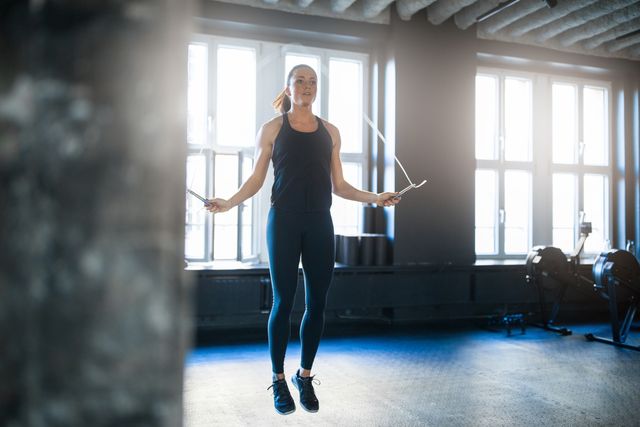 sporty woman doing workout with jump rope in gym