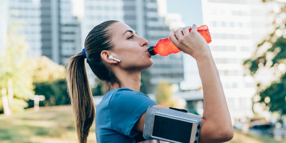 sporty woman drinking water after exercise