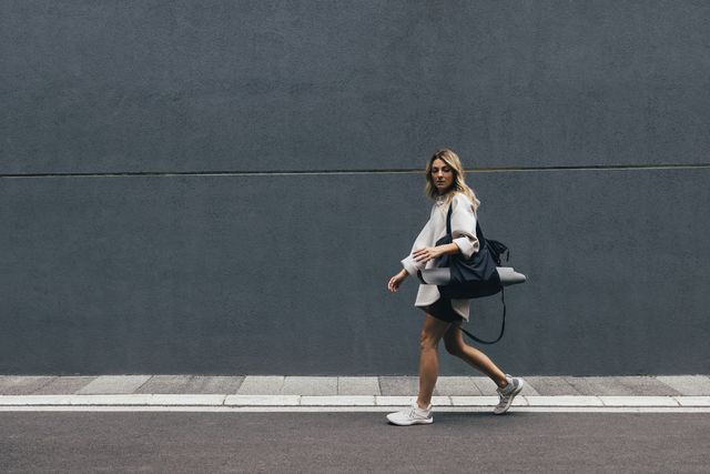 sporty woman in a white sweatshirt walking in city