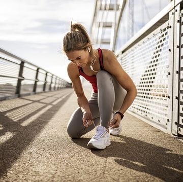 sporty woman tying shoelace on a bridge before running