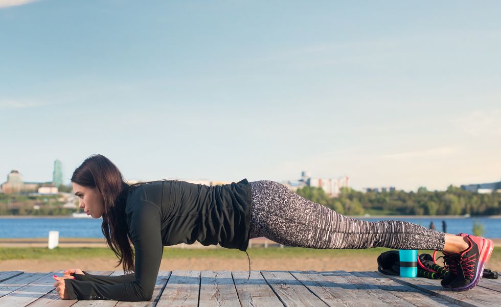 Sporty young woman doing elbow plank exercise working on abdominal