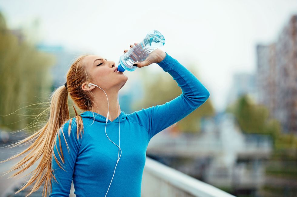 sporty young woman drinking water on bridge