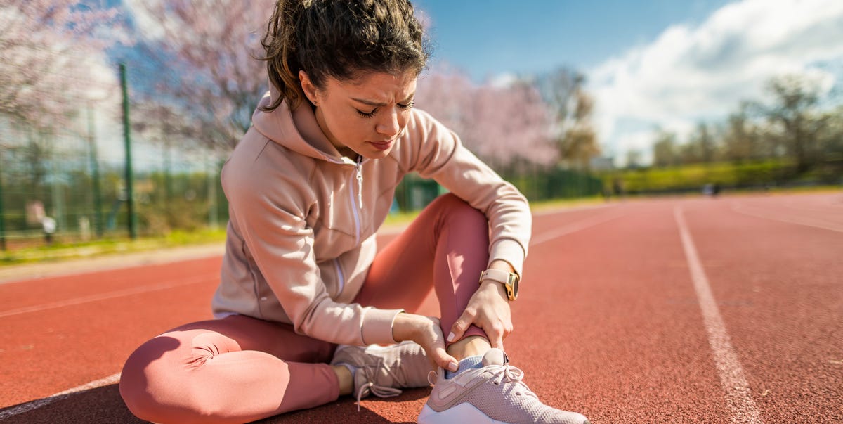 vrouw met pijn aan achillespees op atletiekbaan