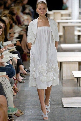 a model in a white dress with rosettes