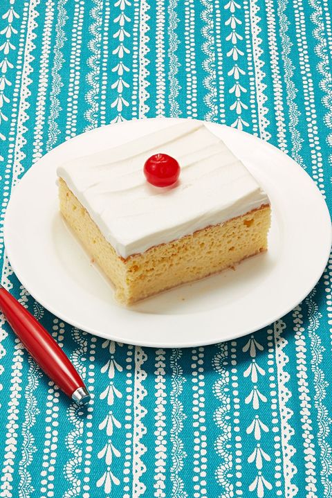 spring cake recipes tres leches cake slice on white plate with cherry and red fork