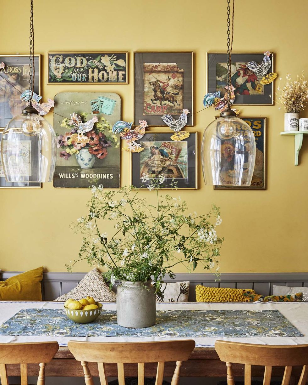 a table with pretty blooms in a crock in front of a mustard yellow wall