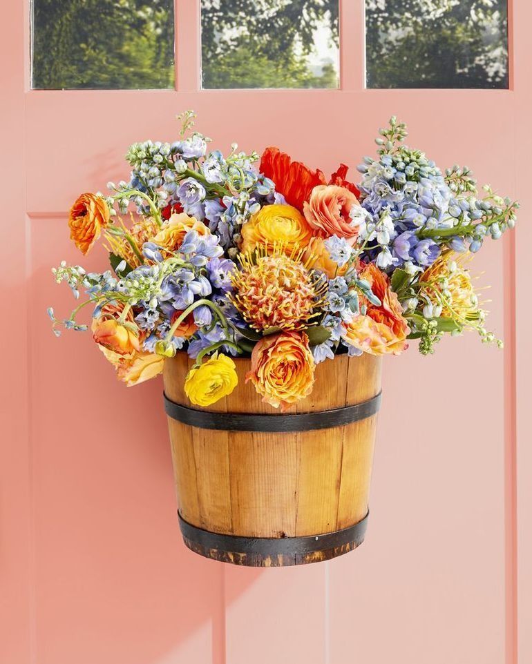 bucket of colorful flowers hung on a pink door for spring decorating idea