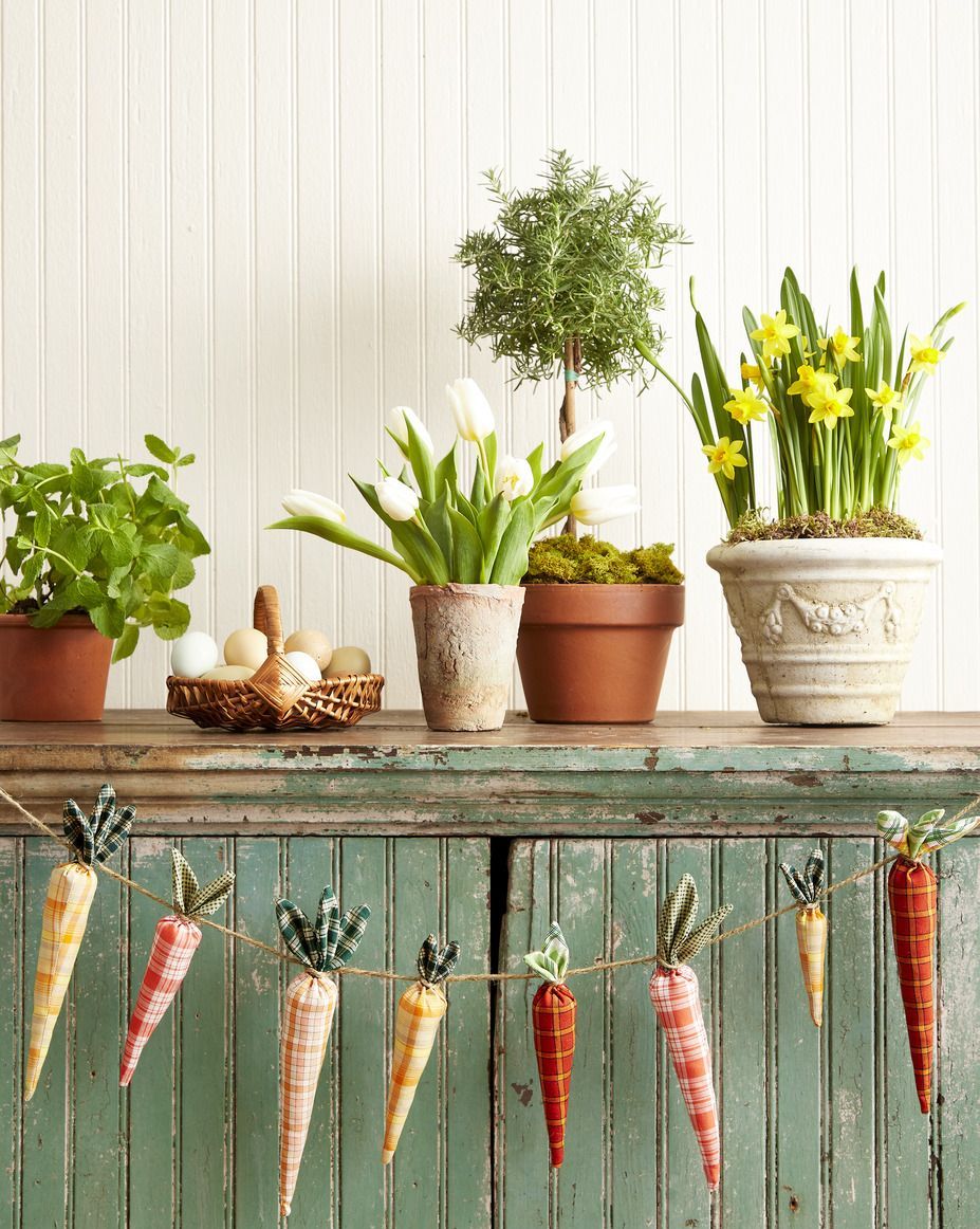 spring decorating ideas for buffet including fabric carrot garland, basket of eggs, white tulips, topiary, potted daffodils
