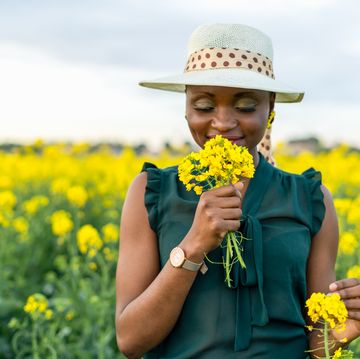 woman portrait holding and smelling yellow flowers bouquet on colorful countryside field