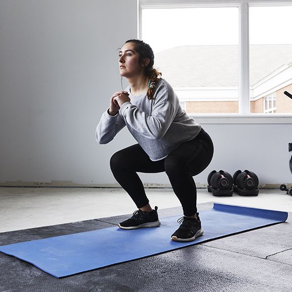 young woman squats in home gym