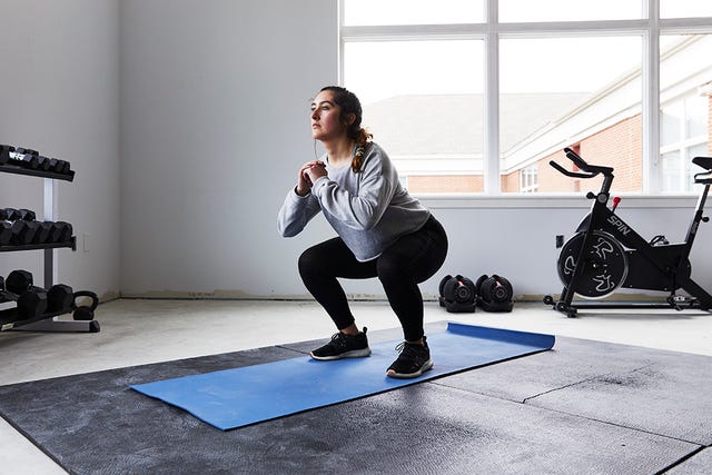 young woman squats in home gym