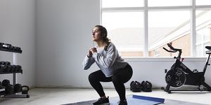 young woman squats in home gym