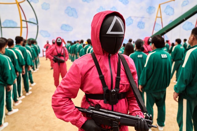 a squid game guard with squid game players