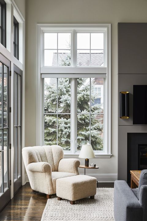 white lounge chair, fireplace, cream walls, cream rug, wooden flooring