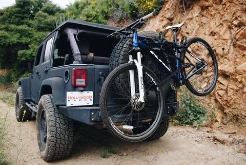 bike mounted to spare tire of jeep on dirt road