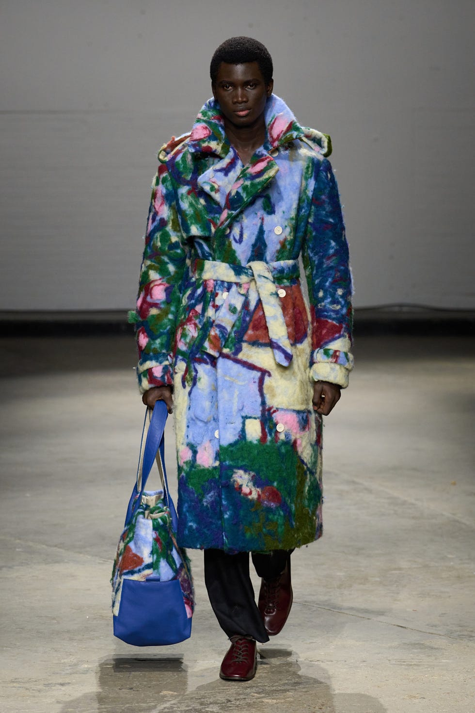 Model wearing a colorful artistic coat and carrying a matching bag