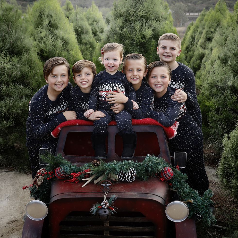 group of kids around a car in tree field