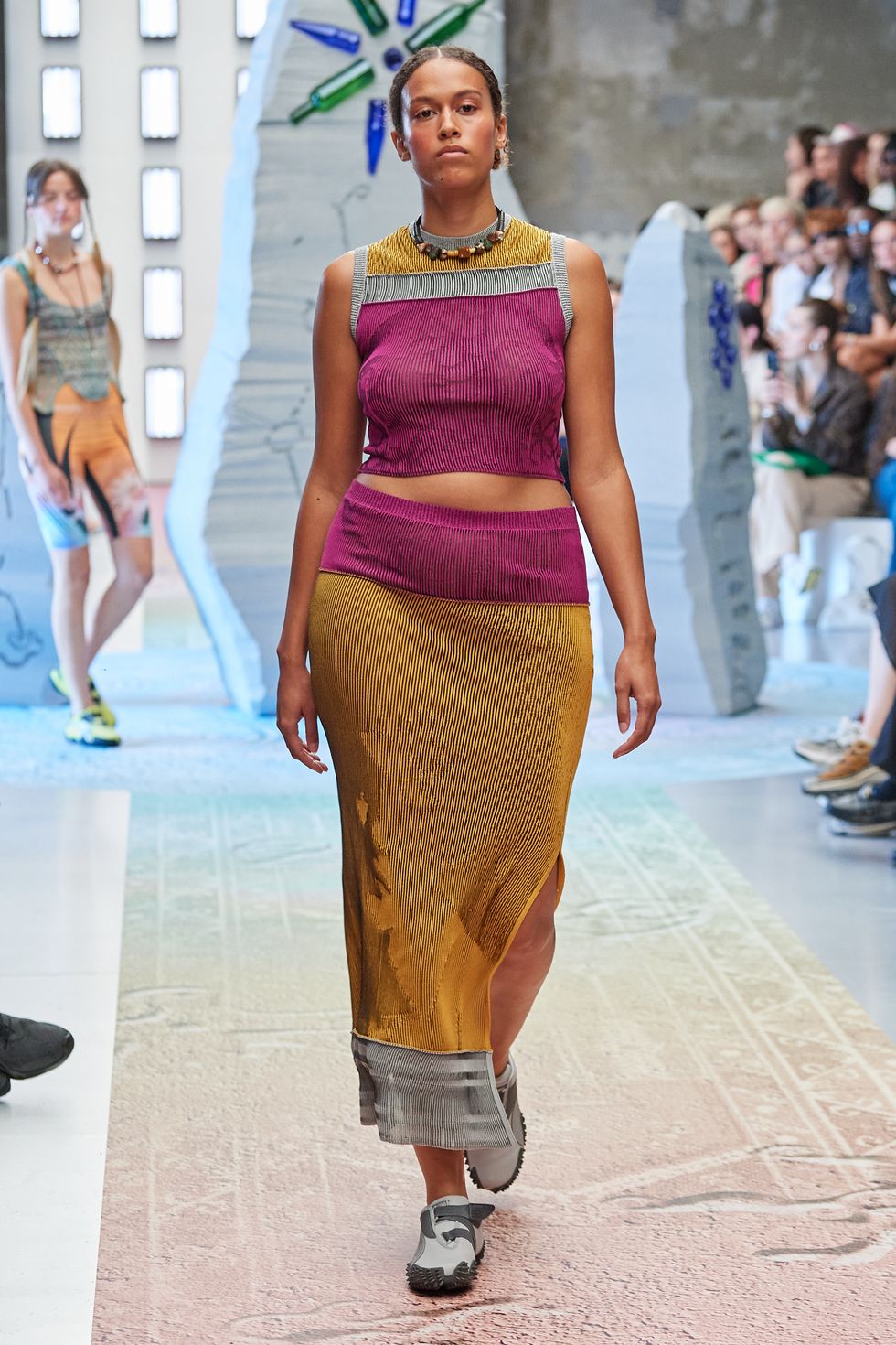 a model walks at paolina russo wearing a matching knit set and sneakers
