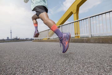 runner in colorful gear on a bridge with a city skyline in the background