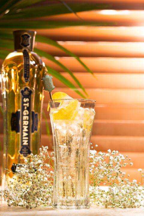 clear glass with bubbly drink topped with lemons, flowers behind