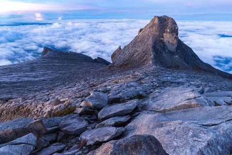 De eerste zonnestraal valt op St Johns Peak met een zee van wolken op de achtergrond Gua Paka in Sabah Maleisi