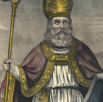 a drawing of saint patrick wearing white robes, a red cap with gold trim, and a gold pointed hat, he is holding a gold staff in one hand and an open book in the other while looking upward toward the sky