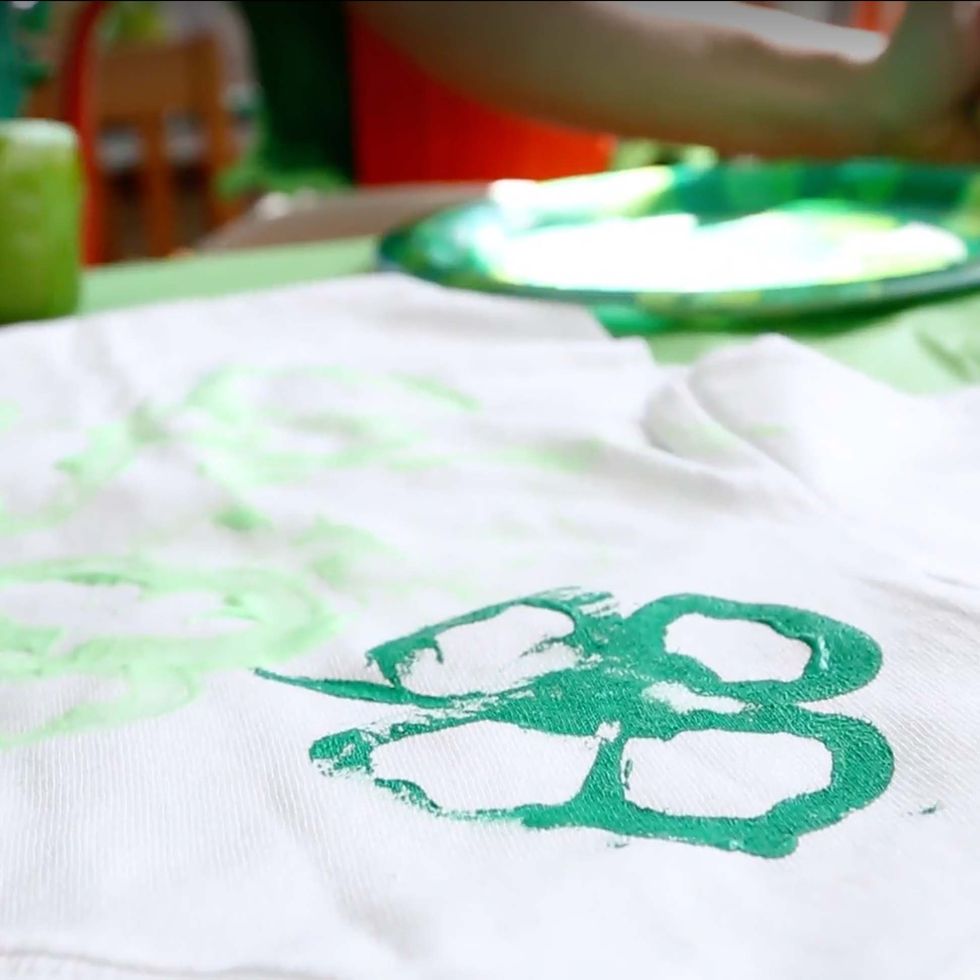 green outline of four leaf clover stamped on fabric using a cut bell pepper as a stamp