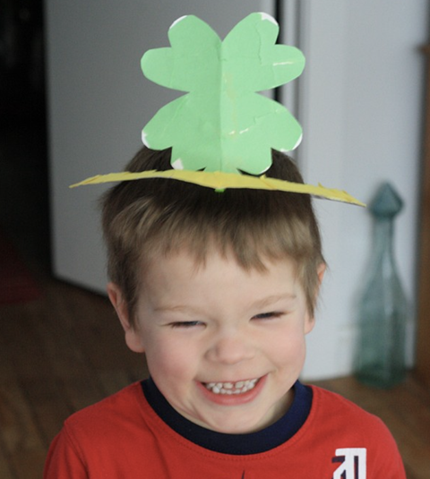 st patrick's day crafts, boy smiling wearing a paper plate clover crown