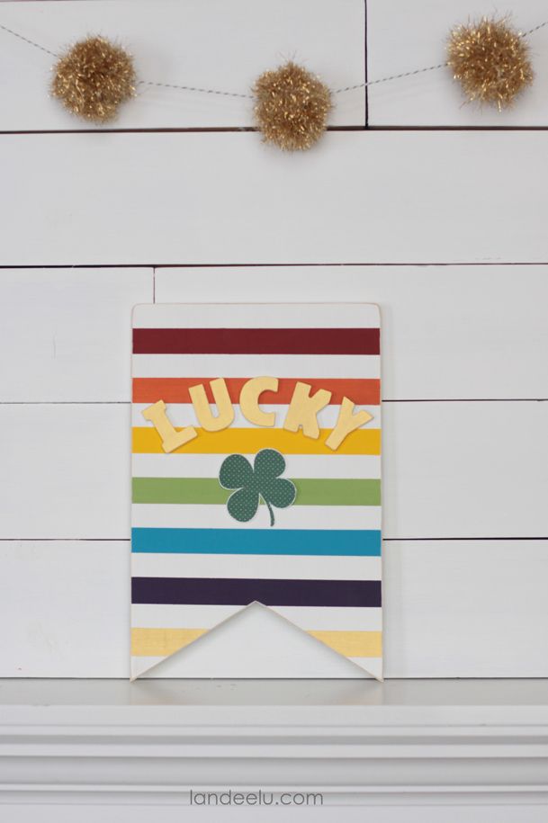 st patricks day sign craft that says lucky with a shamrock emblem on a background of white and multicolor stripes