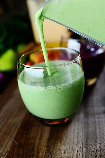 healthy green smoothie in short glass being poured