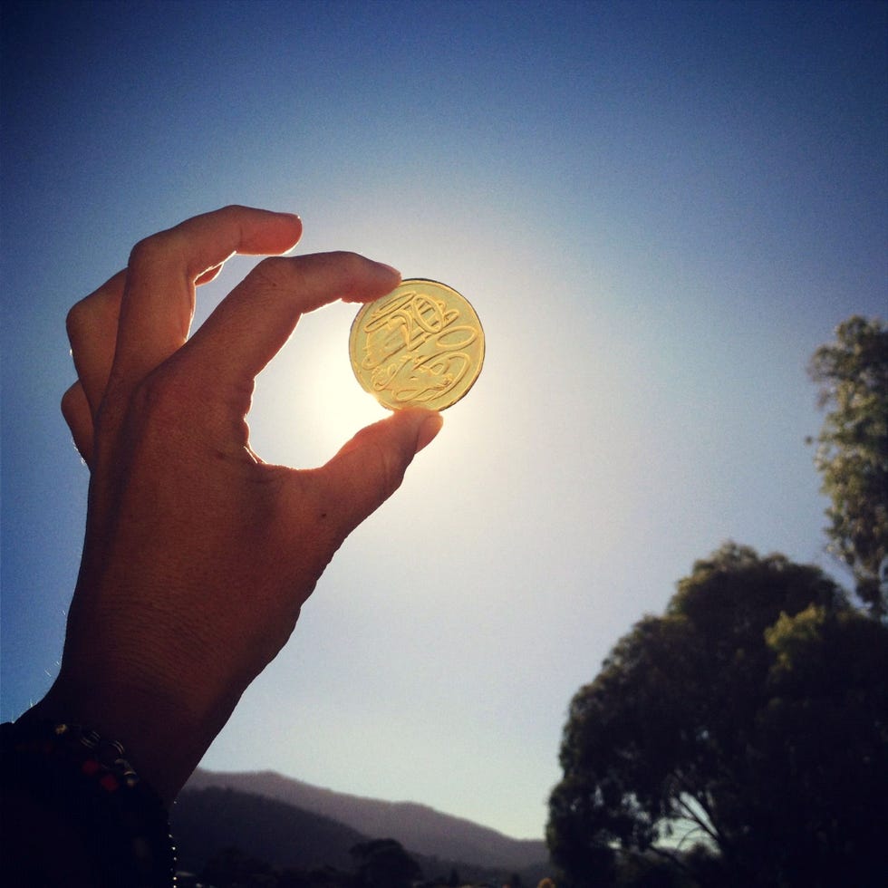 hand holding a gold coin up to the sky after a round of the saint patrick's day game find the coin