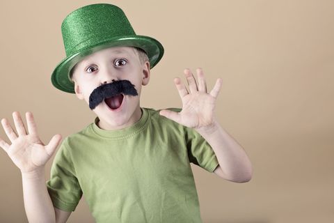 boy wearing green top hat and fake mustache making funny face