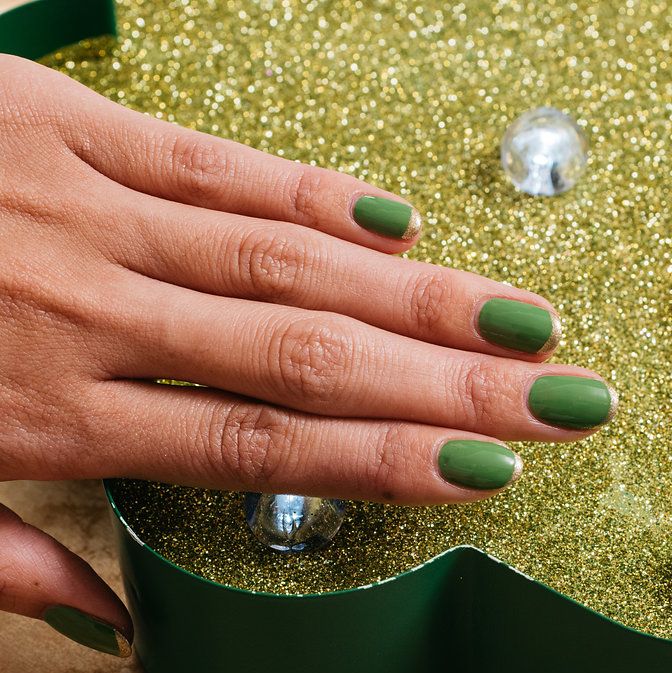 a hand with painted fingernails in green polish with gold tips