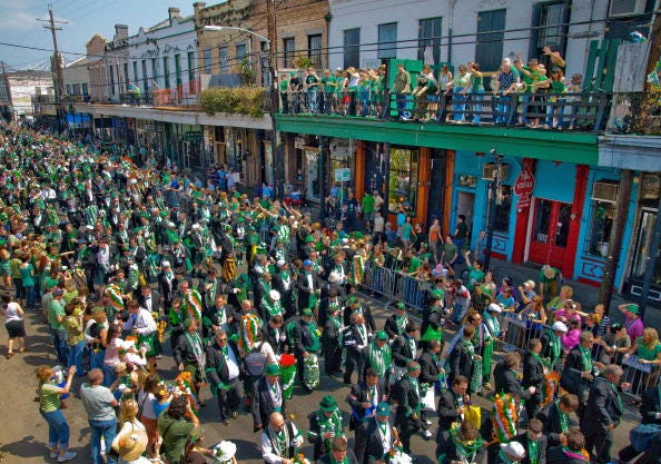 huge parade and crowds on sidewalks with more people on balconies in new orleans