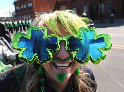 woman beside parade route wearing giant green glasses in the shapes of shamrocks