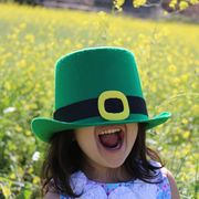 little girl with leprechaun hat in field of flowers