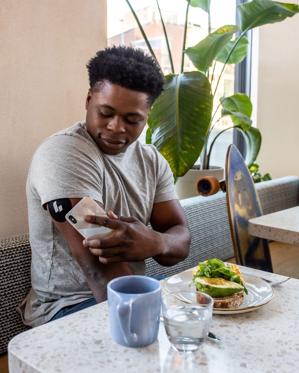 man measuring his glucose levels with app at table at restaurant