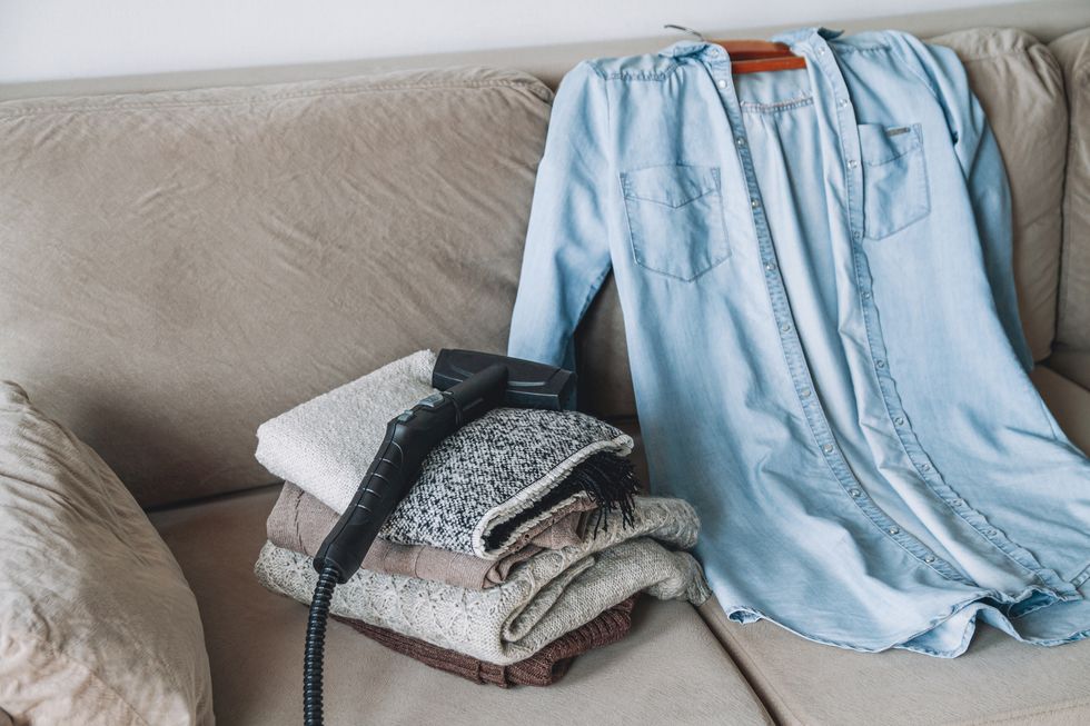 a stack of clean warm clothes and shirt with a steam cleaner on