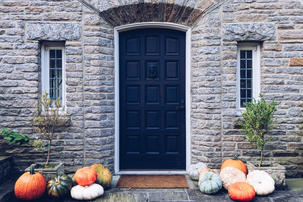 stack of fancy pumpkins & gourds on front porch of tudor home stack of fancy pumpkins gourds on front porch of tudor home