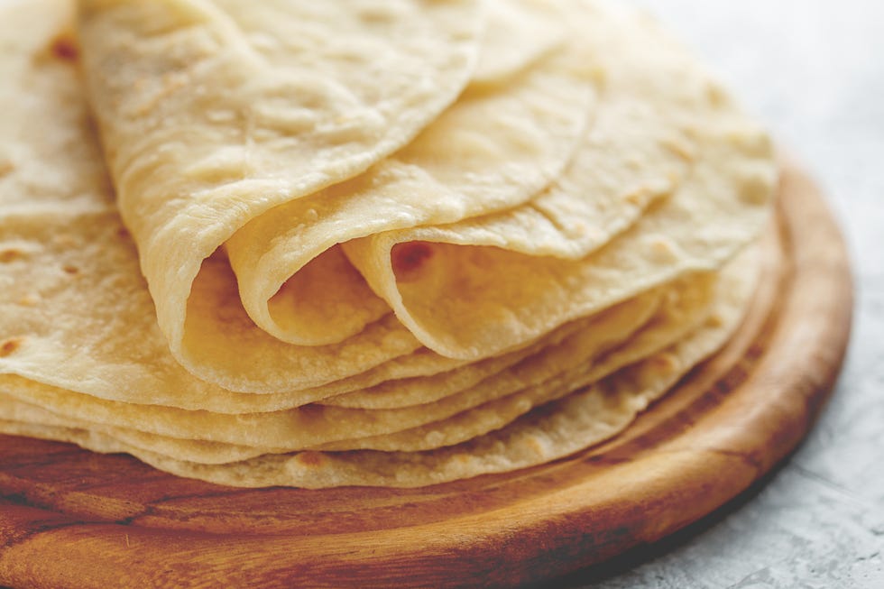 stack of homemade wheat flour tortilla wraps on wooden cutting board
