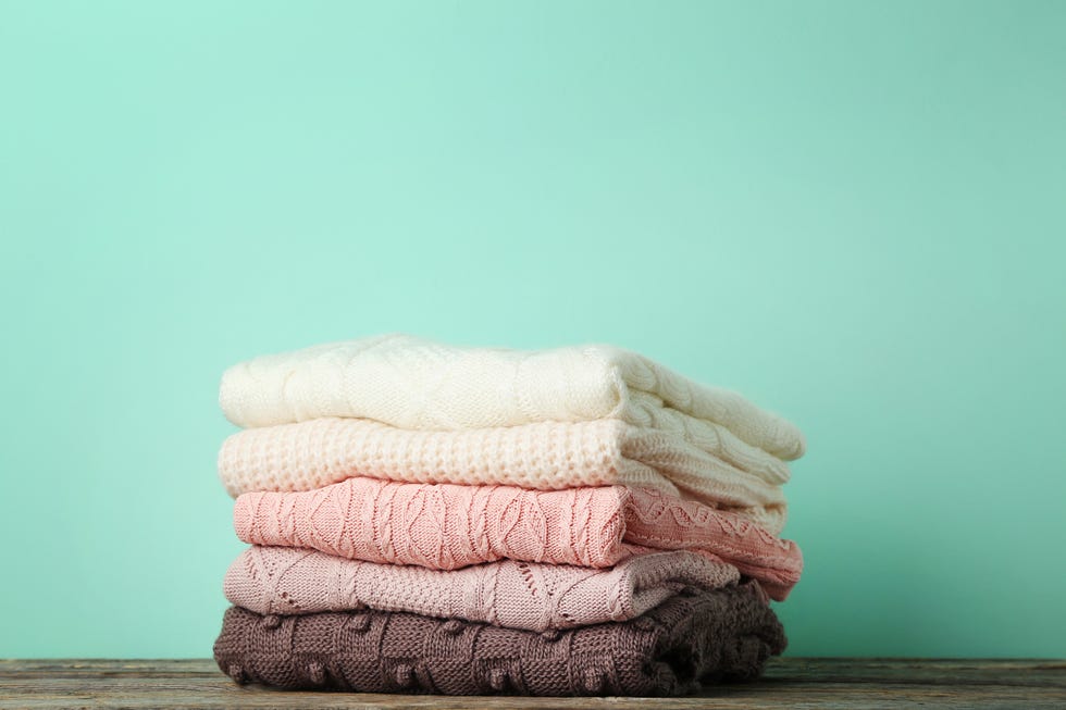 Stack of knitted sweaters on mint background