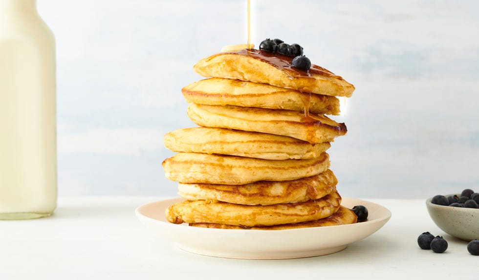 stack of pancakes with blueberries and maple syrup in plate on table
