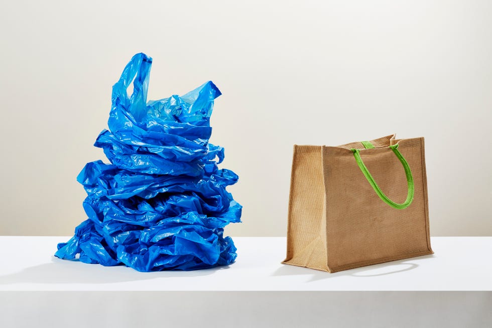 a stack of plastic carrier bags next to a reusable shopping bag
