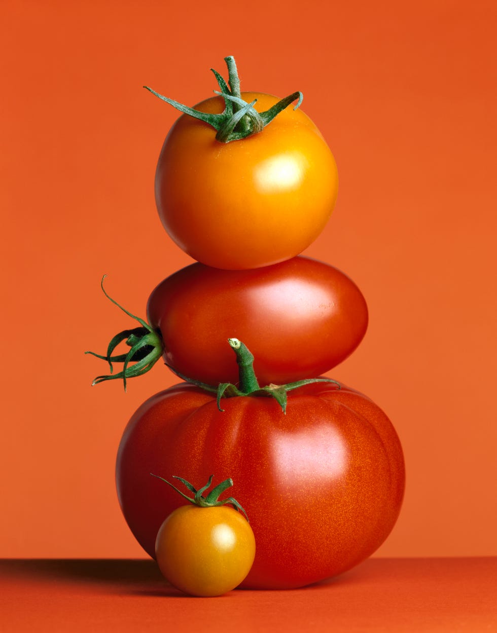 stacked red tomatoes on a red background