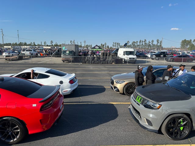 Cars lined up in a racing event with spectators in the background